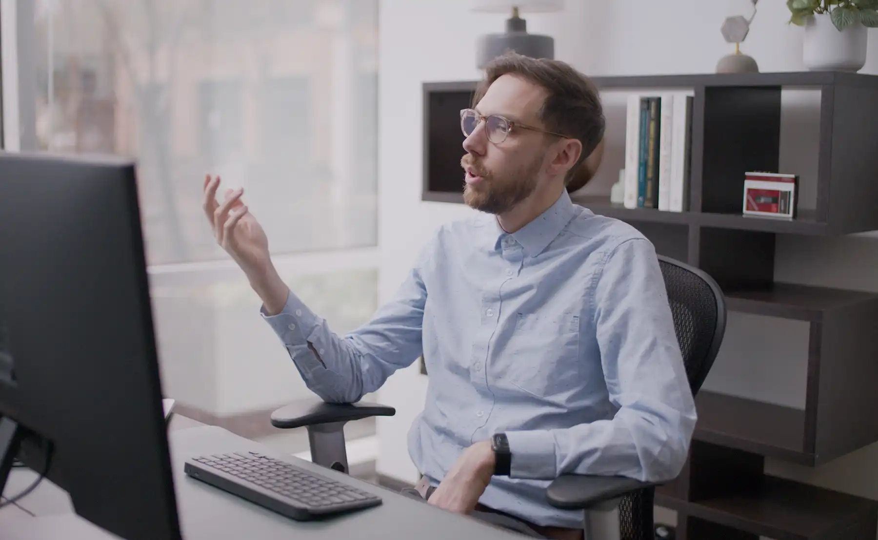 A lead UX designer freely expresses himself and raises questions while gesturing with his right hand during a meeting with the client and software team.