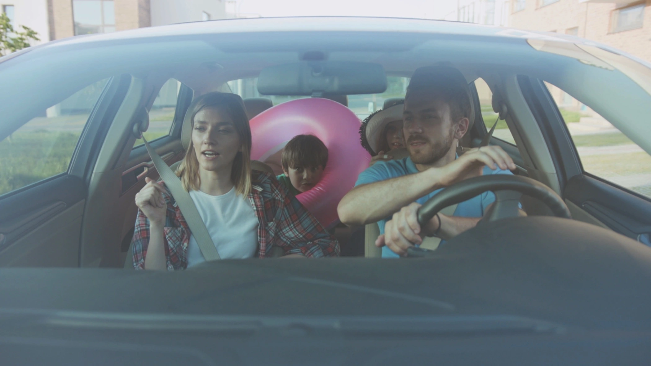 A family of four embarks on a road trip. The father is driving while the mother seems to be giving directions.