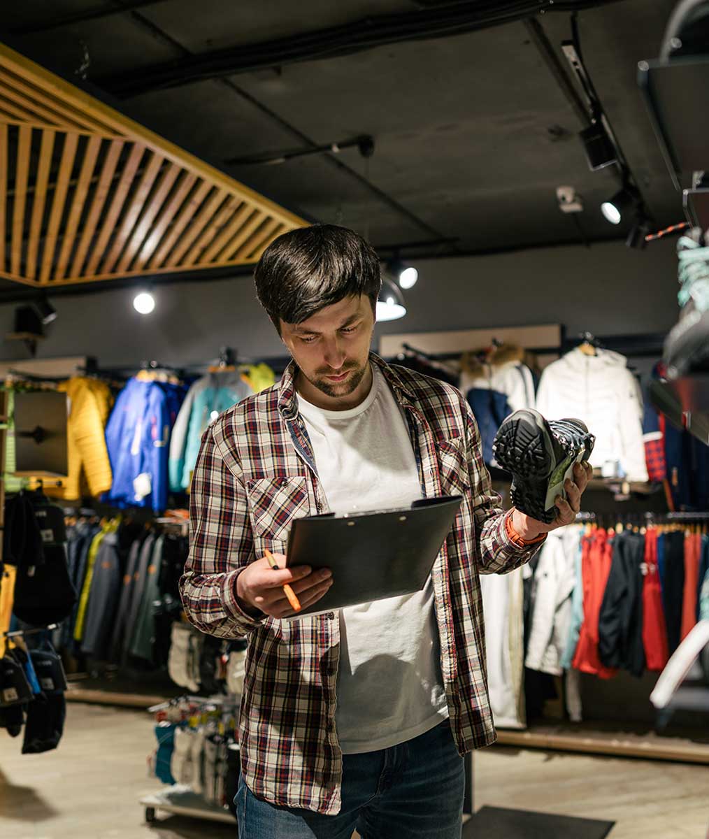 An employee at a sportswear store reviewing and ordering product inventory from his tablet. 