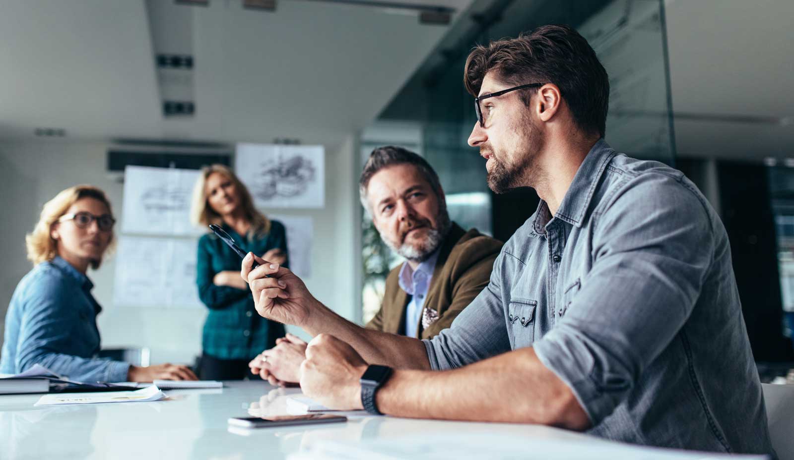 Company meeting where a man is suggesting an idea while his colleagues listen intently.