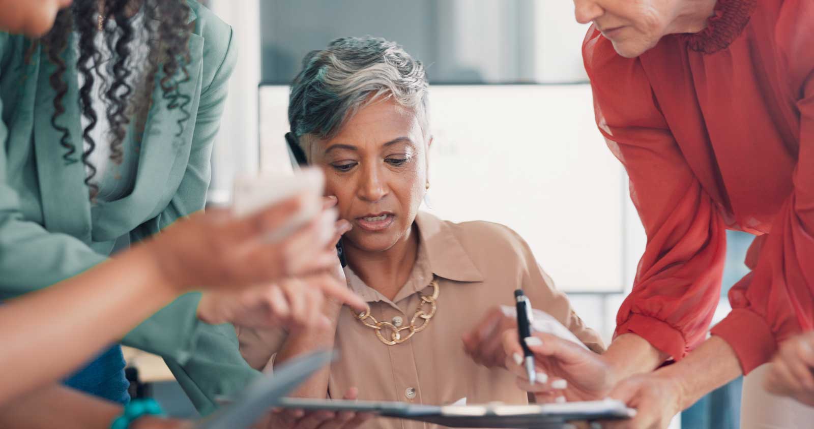 Woman CEO busily handling multiple tasks, several people asking for her input at once. 