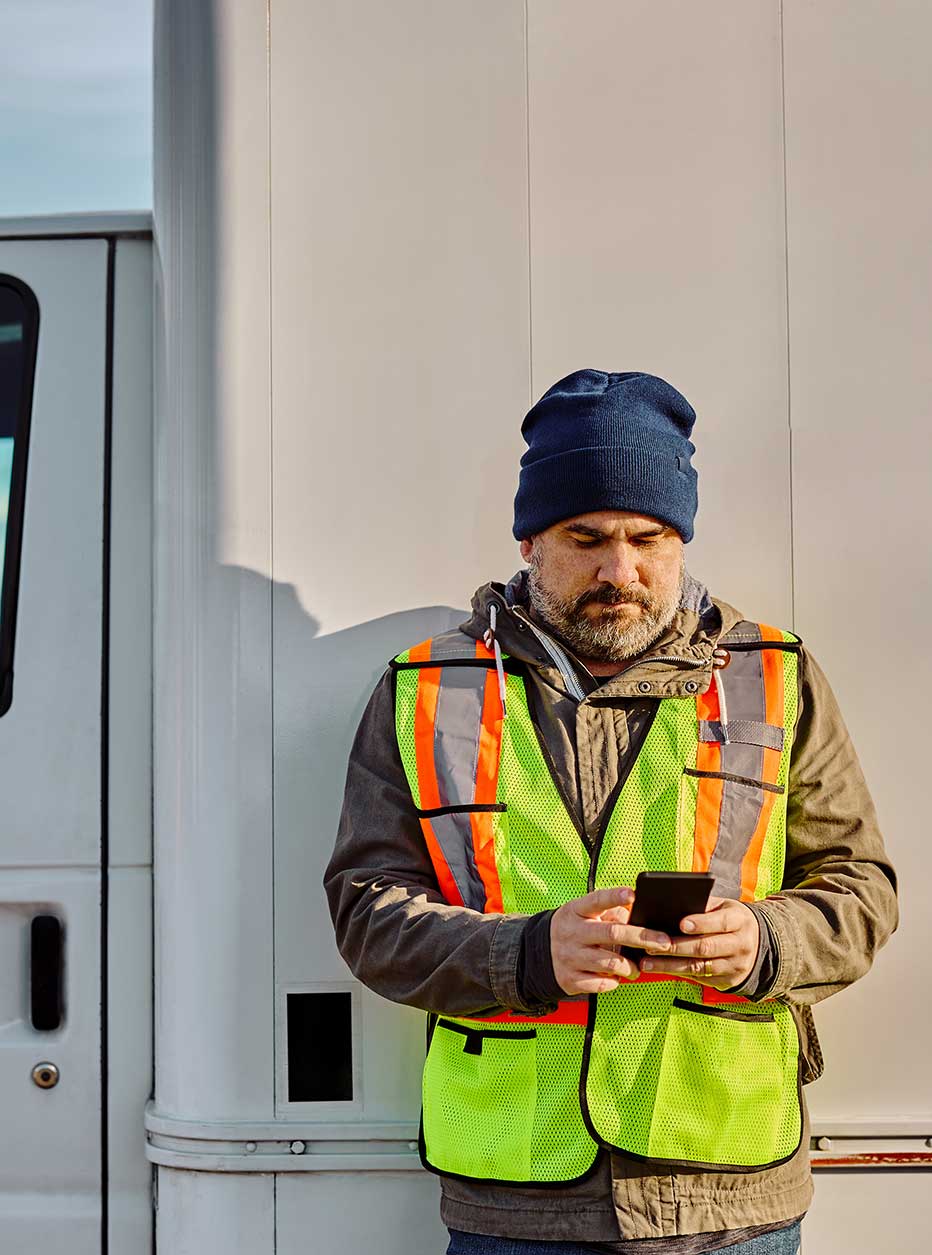 Man in a casual polo using his phone app to accomplish his work.