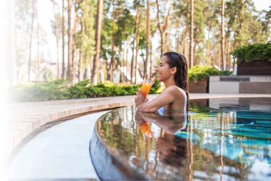 Woman in pool at a resort enjoying her fun drink delivered through the OUTO.ME app. 