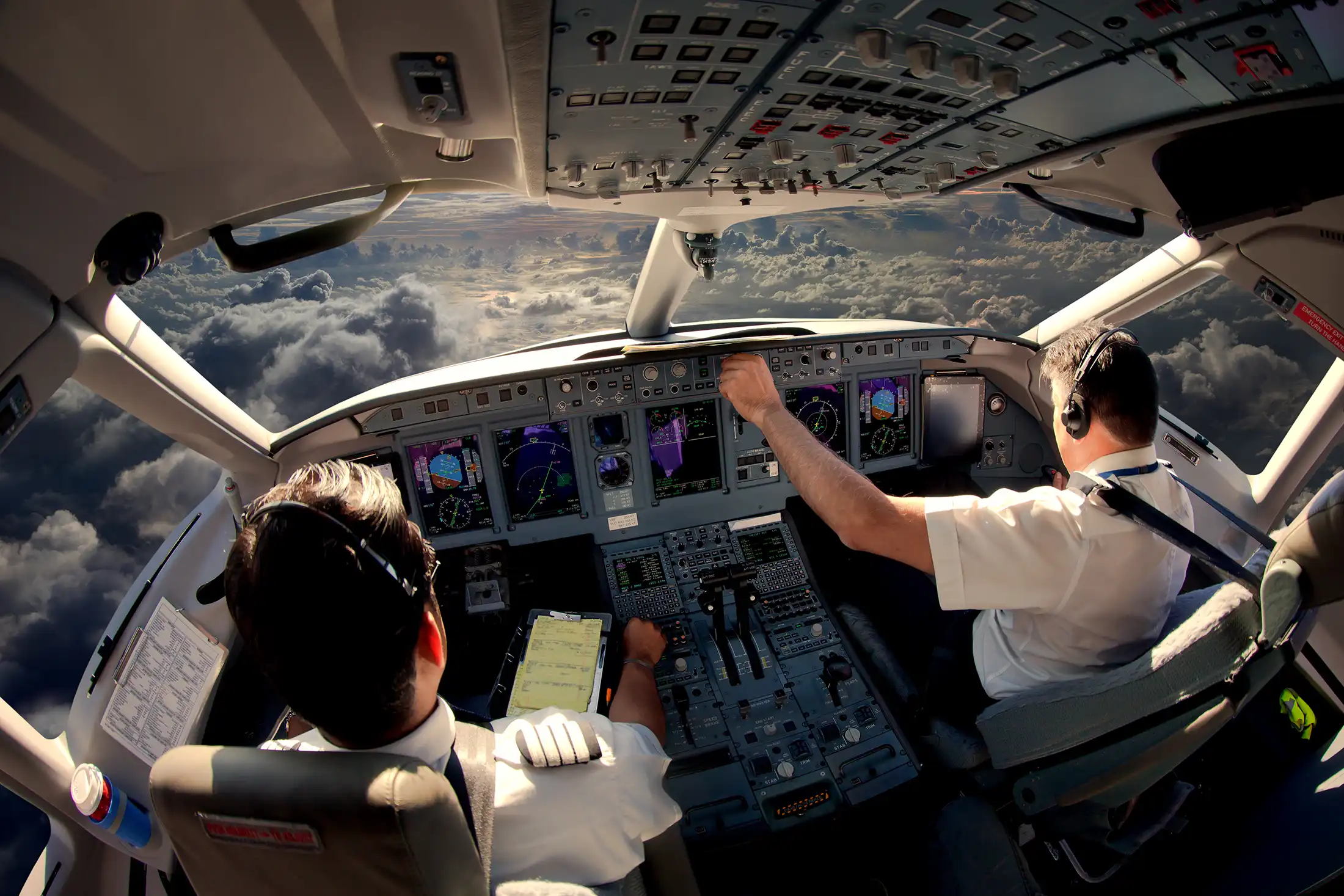 A pilot flies a commercial airliner while his copilot assists.