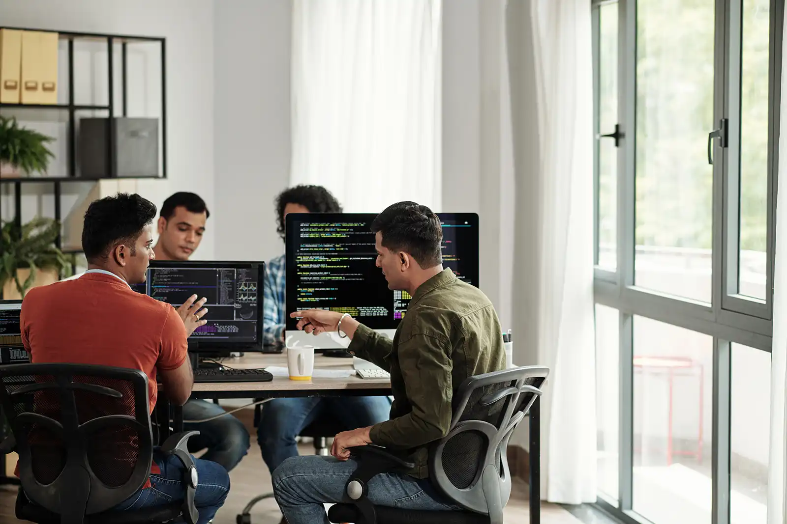 A couple of developers sitting side by side discussing their code