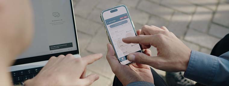 Two hands from two different people pointing to a phone with the Xcite app displayed.