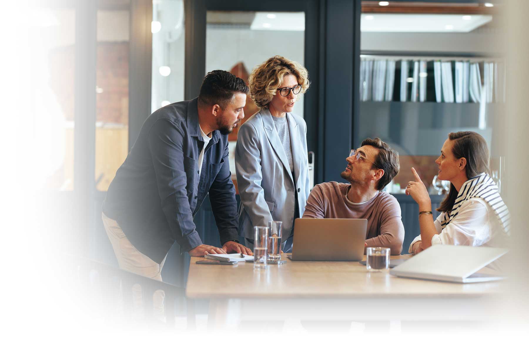 A small team gathered around a laptop in a serious discussion.