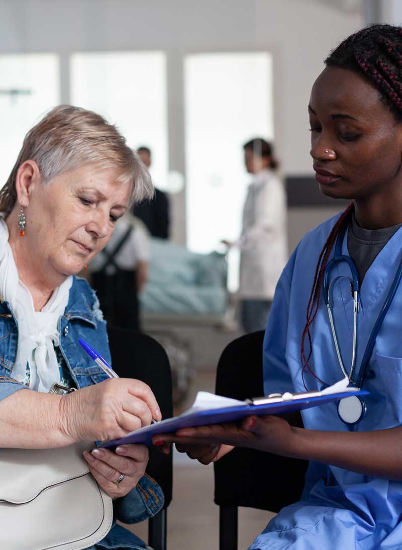 Doctor and patient together with the patient filling out her insurance information on a clipboard.