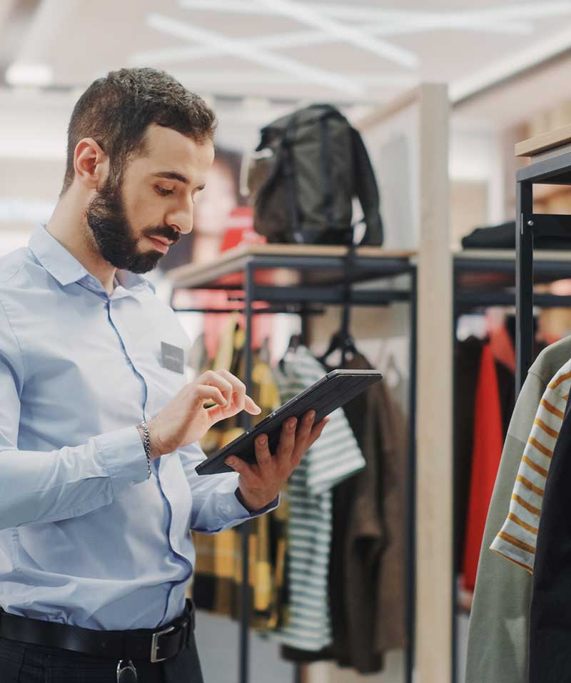 Employee in sports clothing store using his tablet to check and reorder inventory.