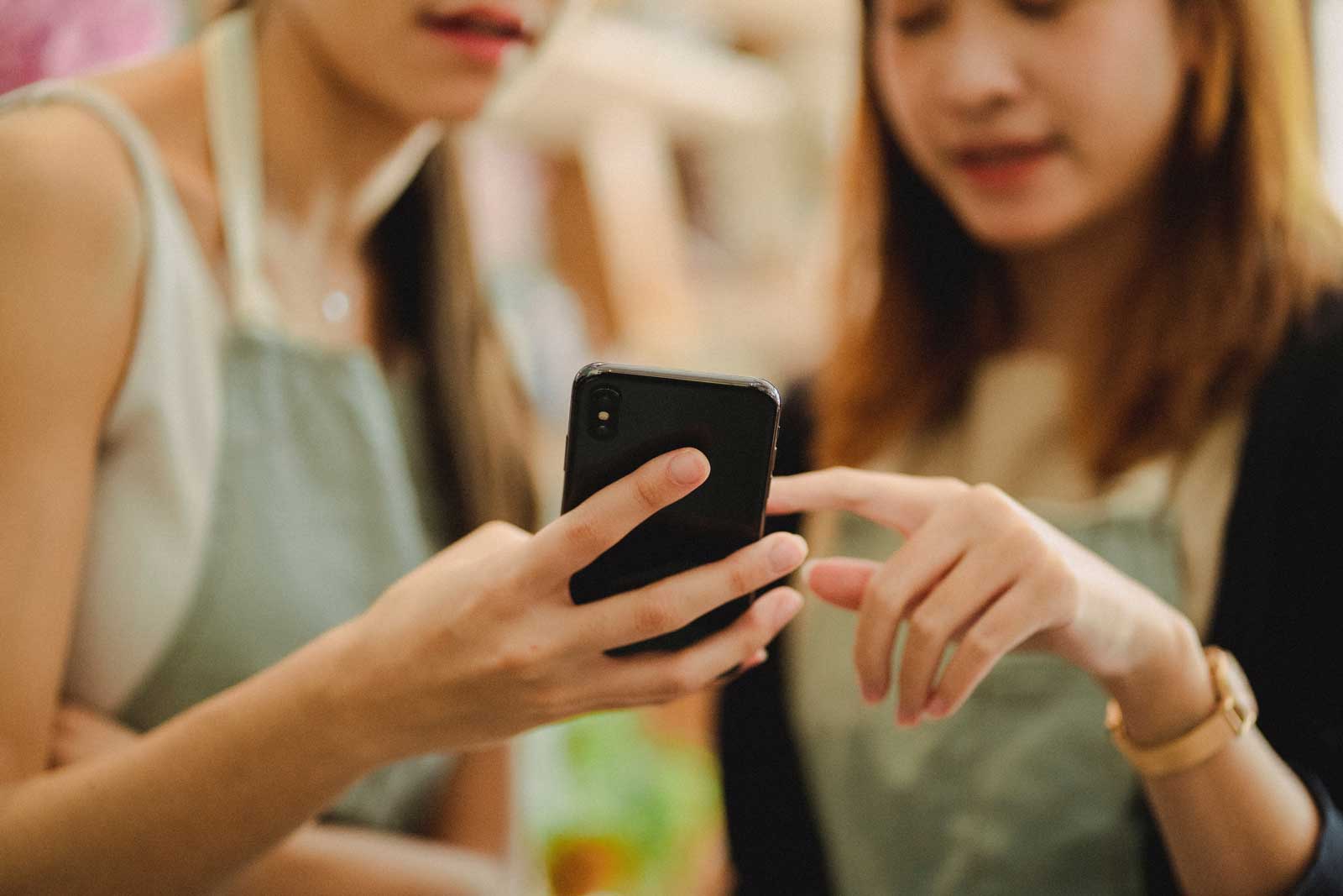 Two apron-adorned employees check their mobile app to accomplish a task on the store floor. 