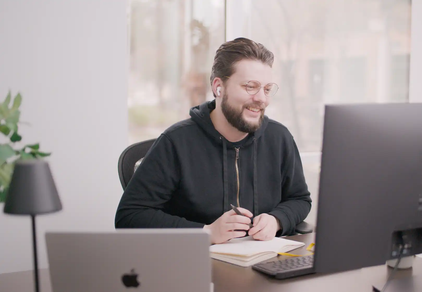 Our Development Coordinator, Paul, sits at his desk, smiling on a client call. 