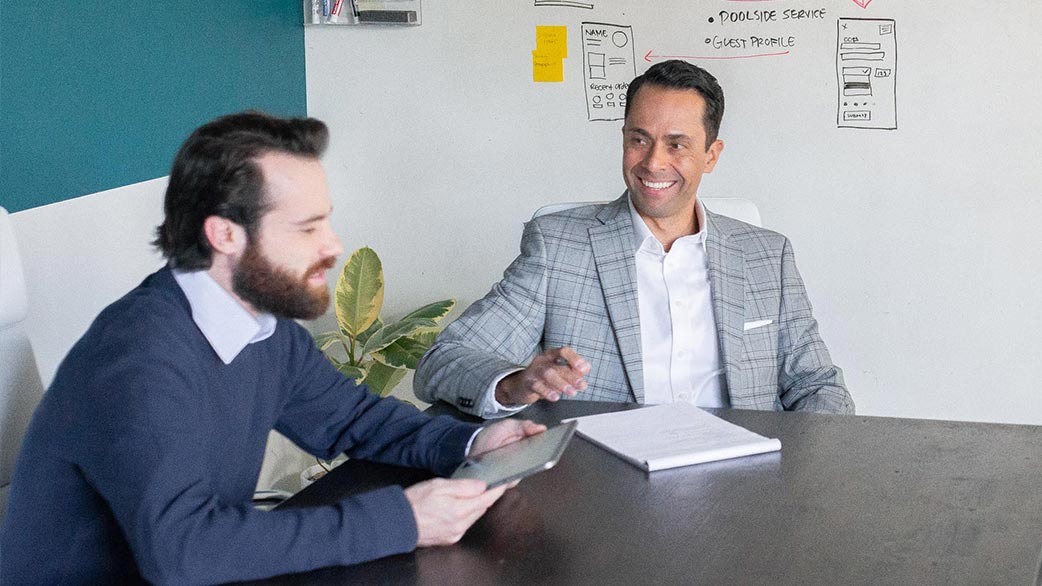 A client sitting with a TSG expert discussing software, the client reviews examples on his tablet.